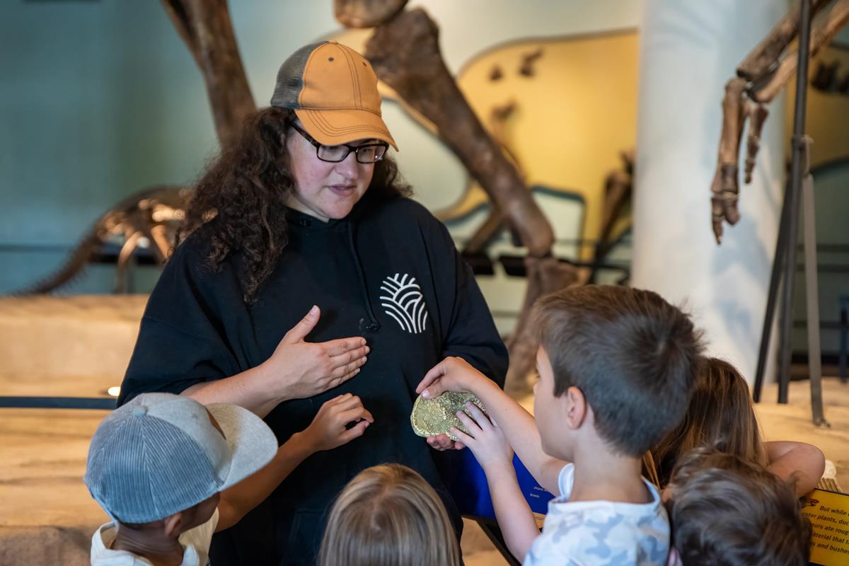 Academy educator shows off fossil imprint to children.