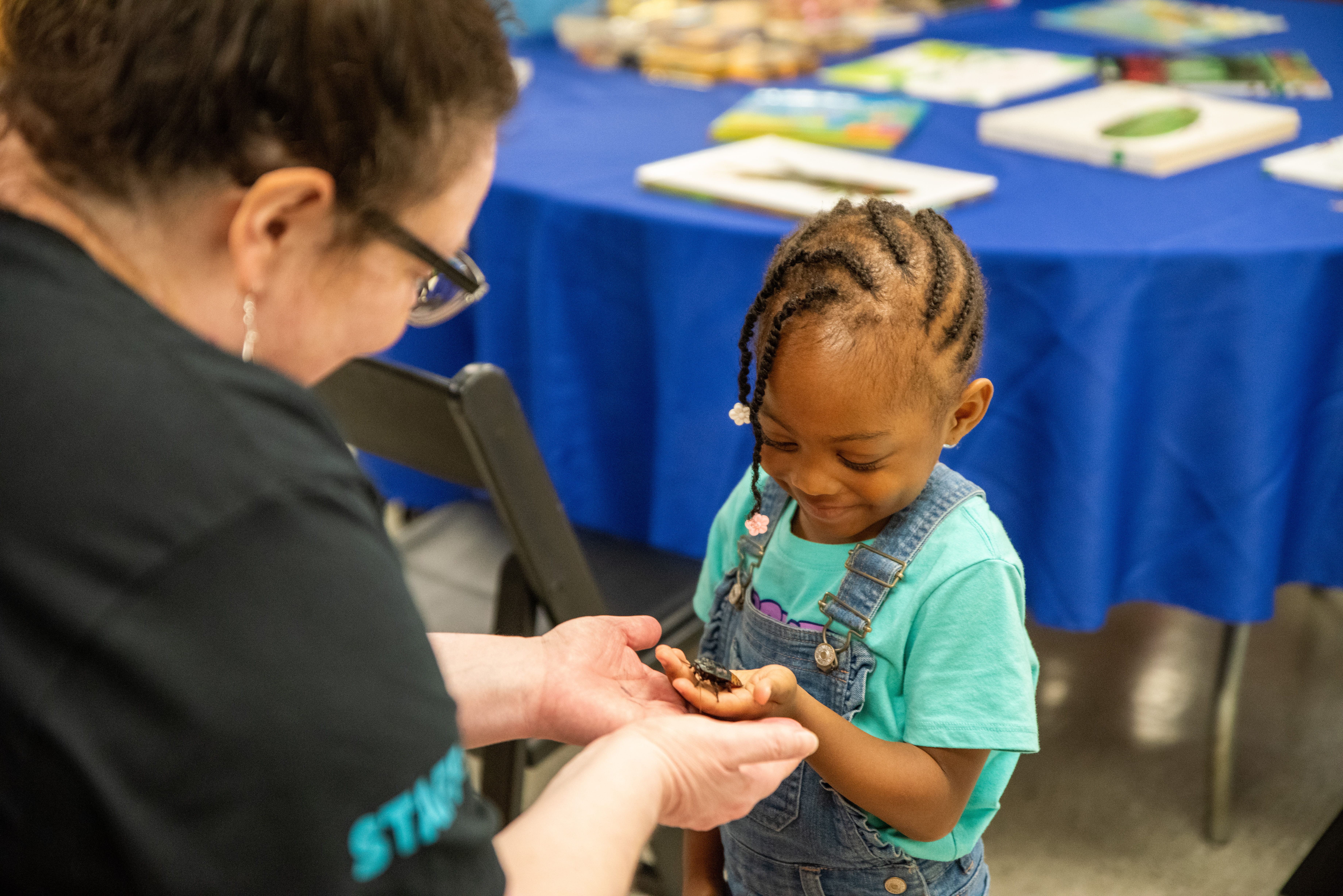An academy educator showing off a specimen to a young child.