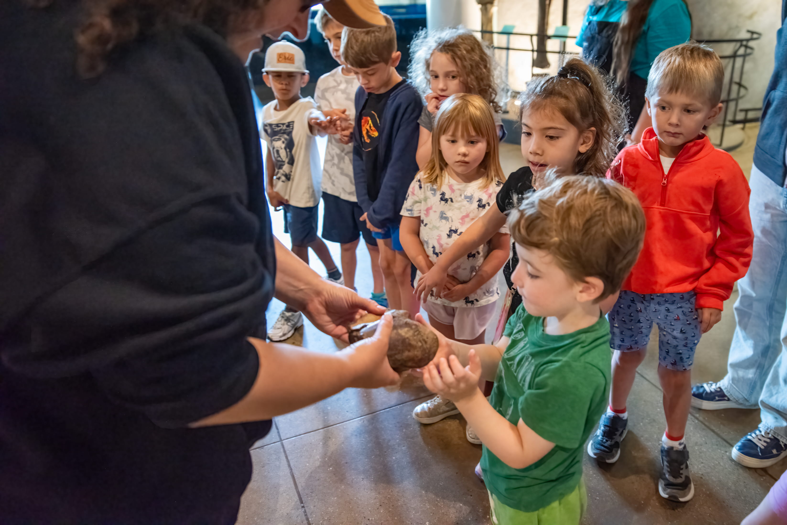 An academy educator showing off a fossil to a group of children.