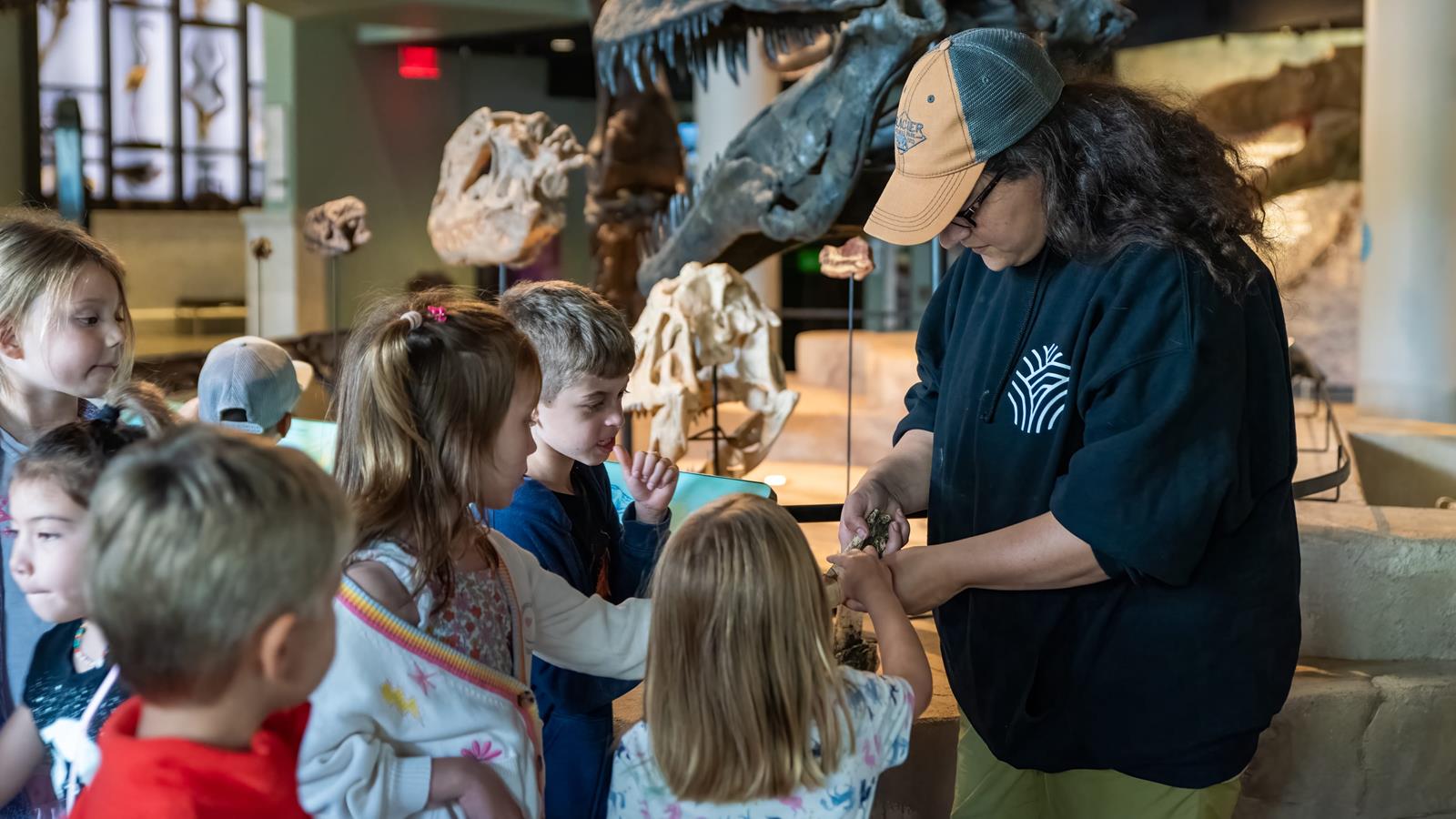 An academy educator showing off a fossil to a large group of children.