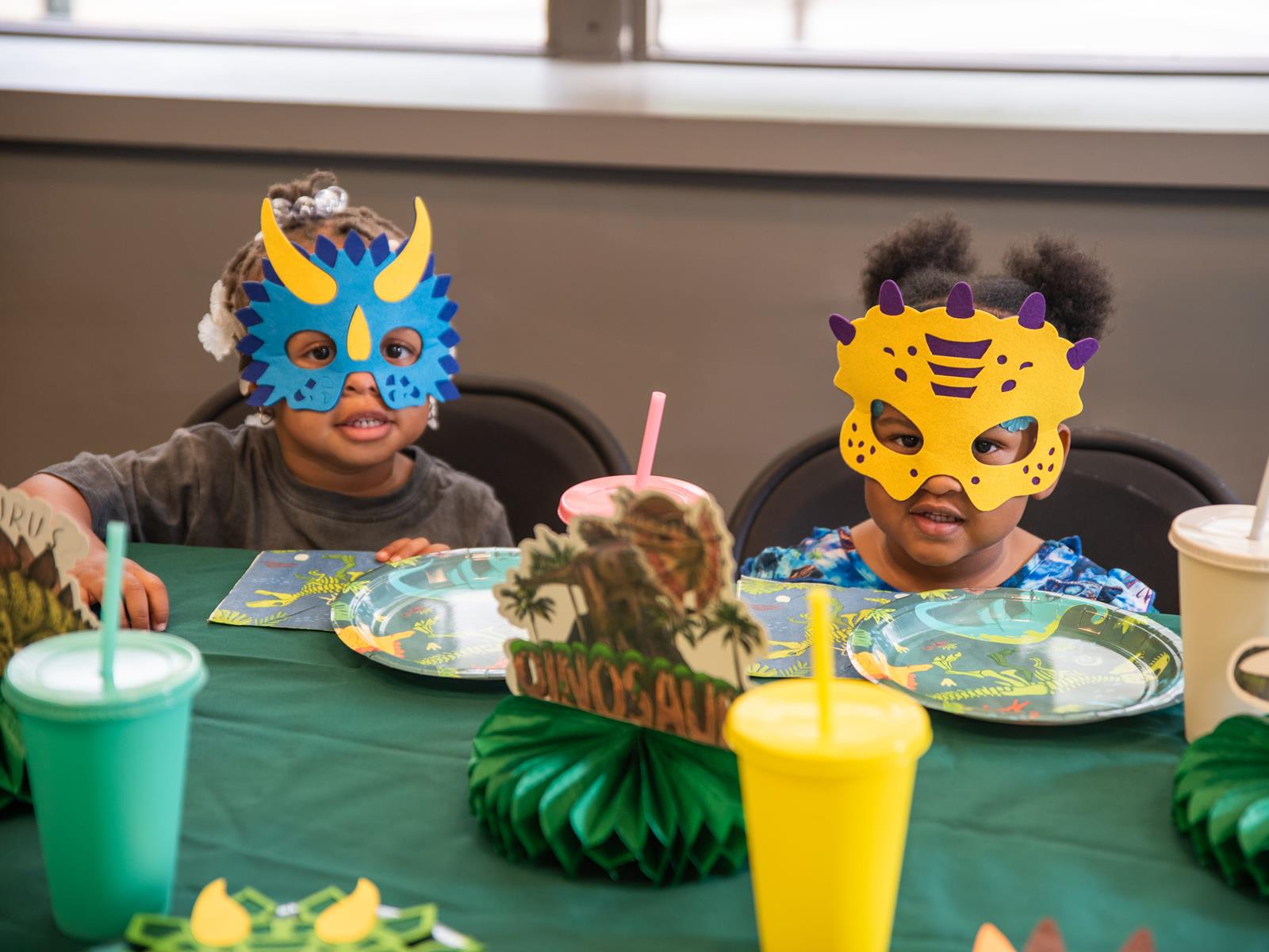 Two children paitently sitting at a table decorated with birthday party decorations.