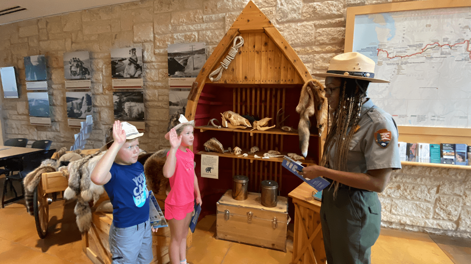 A National Park Ranger being saluted by two children.