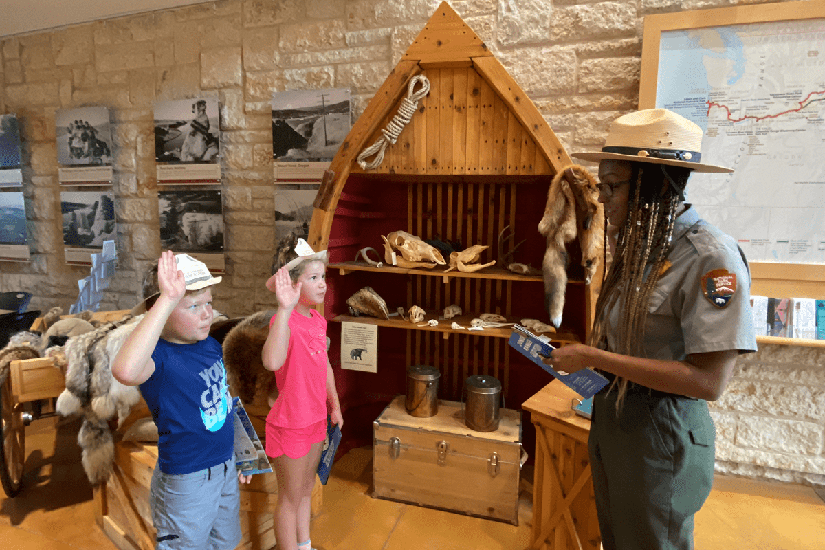 A National Park Ranger being saluted by two children.