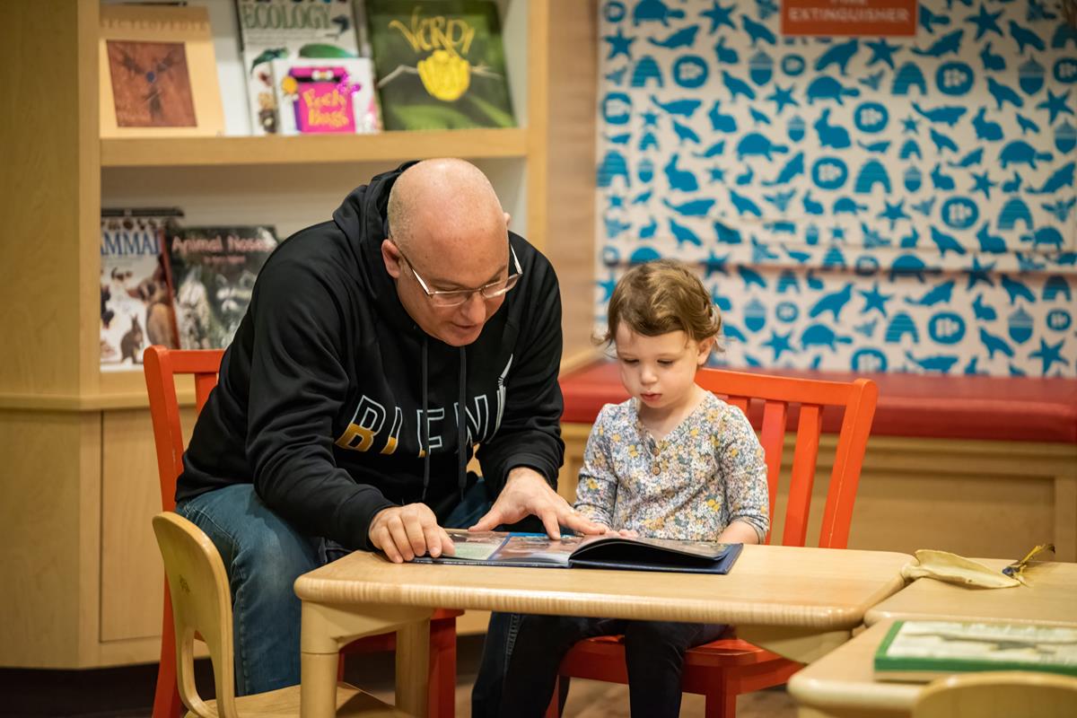 An adult and a child reading a story in Outside-In