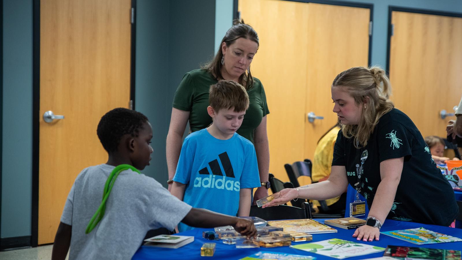 an academy educator shows a specimen to two children.