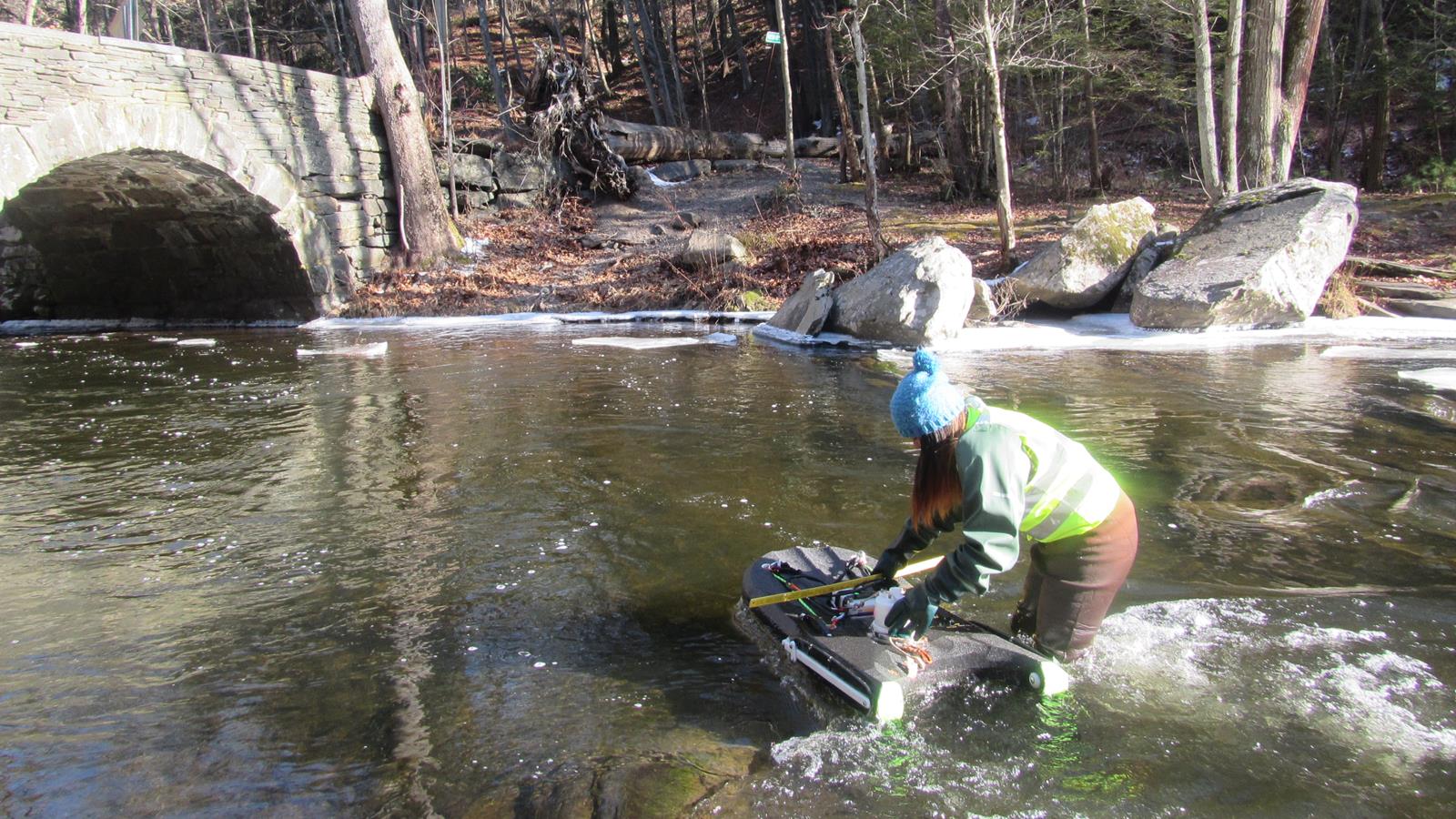 A scientists testing water quality in a river during winter.