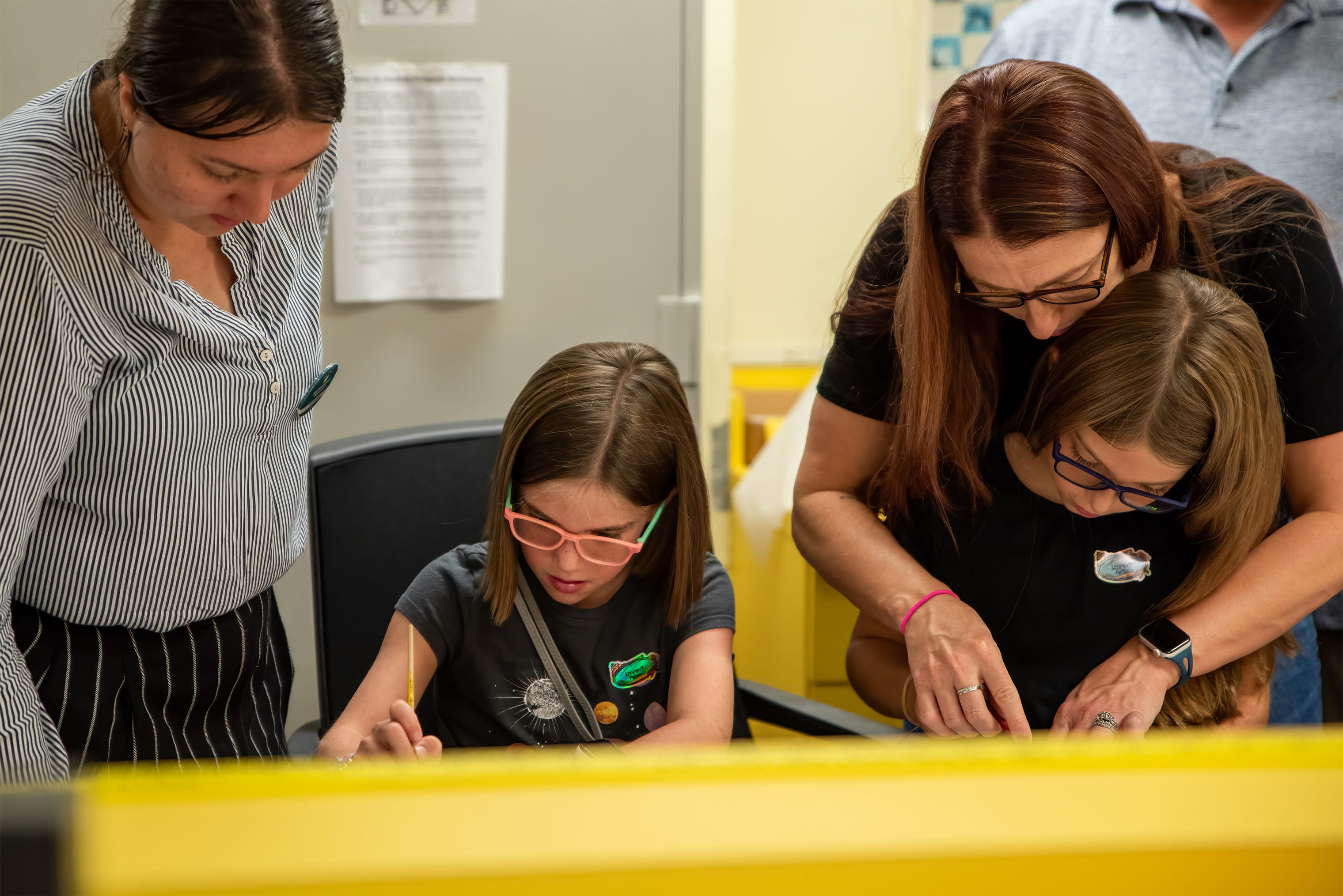 Two adults helping two children work on a craft.