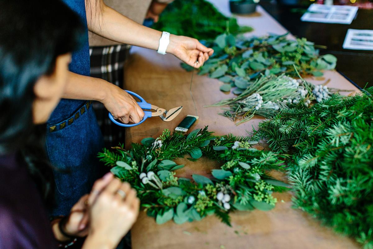 Two people building holiday wreaths