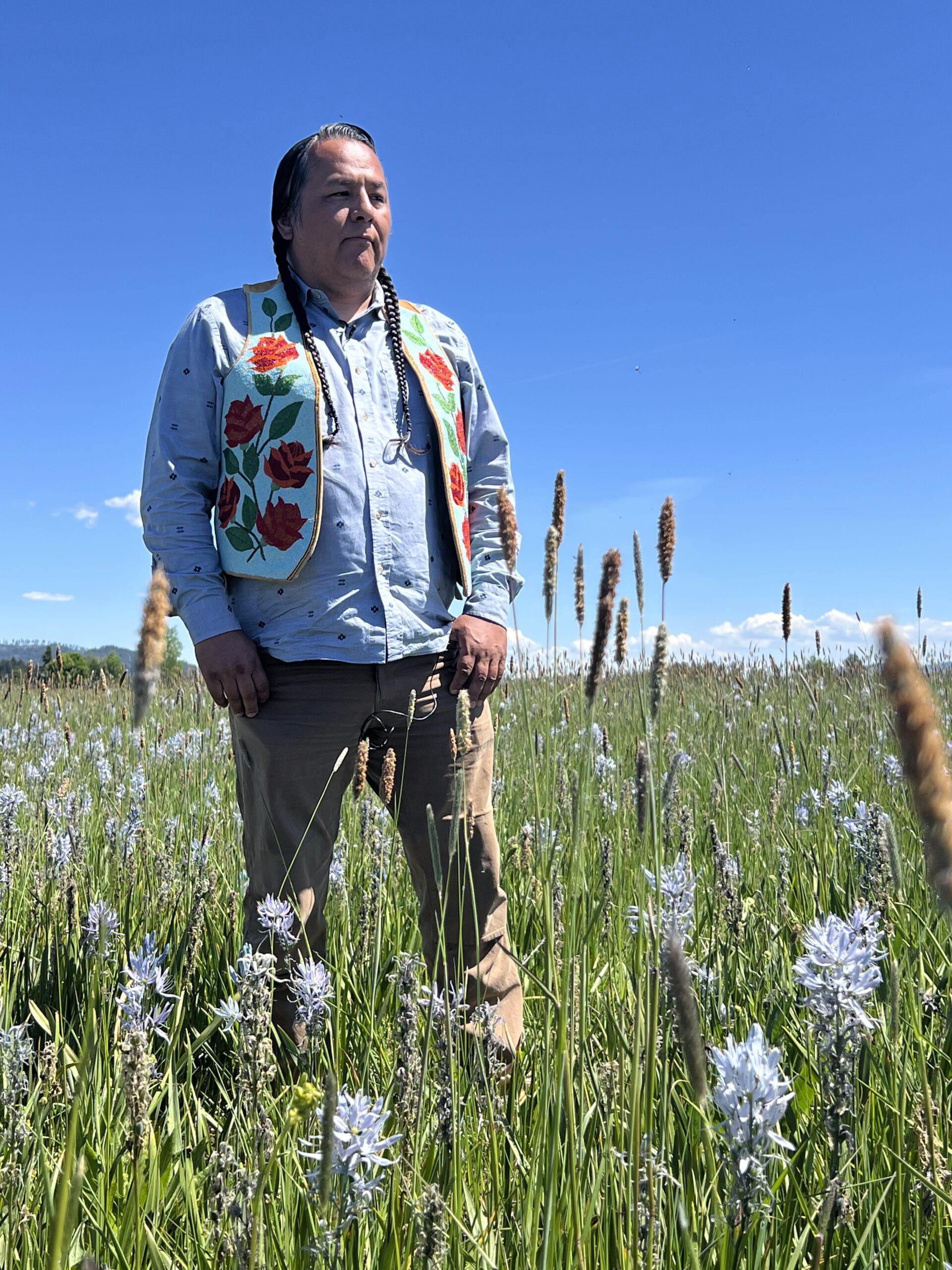 Person wearing a light blue shirt with brown pants standing in a field.