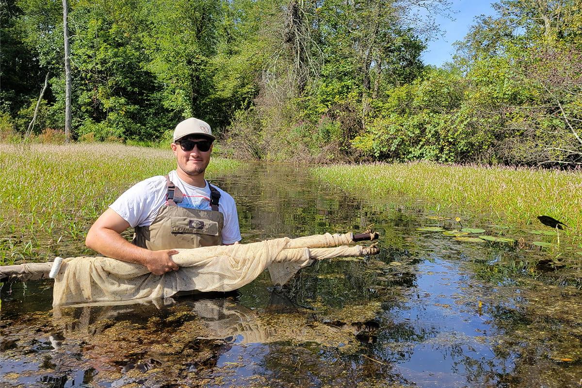 A photo of fisheries research staff, Ean Geller Nocella holding a bundle of fishing nets.