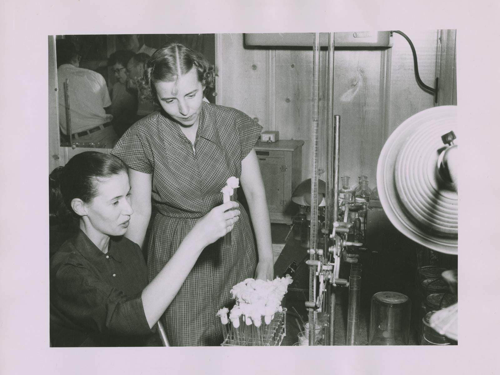 An old photo of two scientists conducting an experiment with specimens in test tubes.