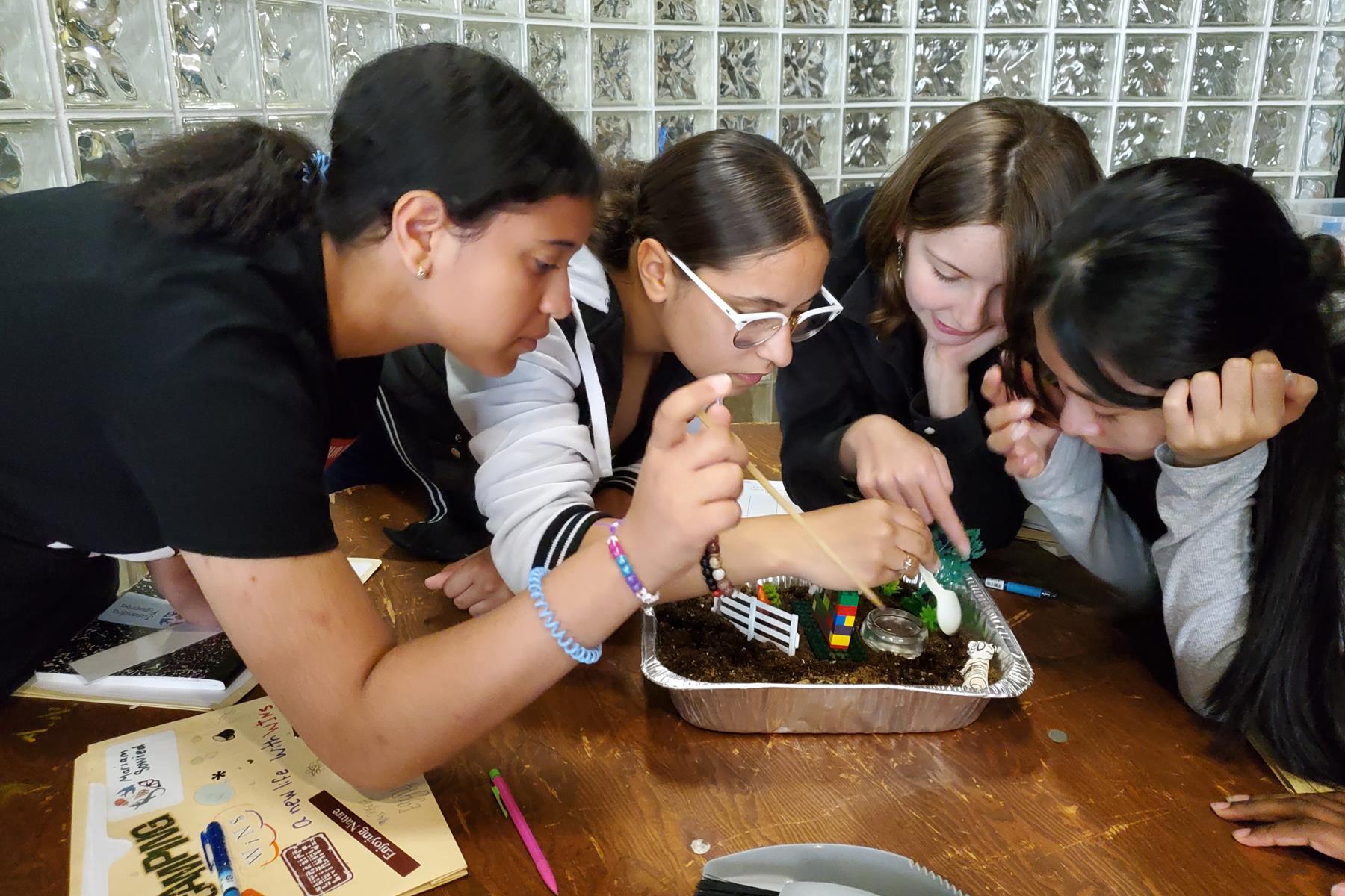 Four students testing soil in a container.