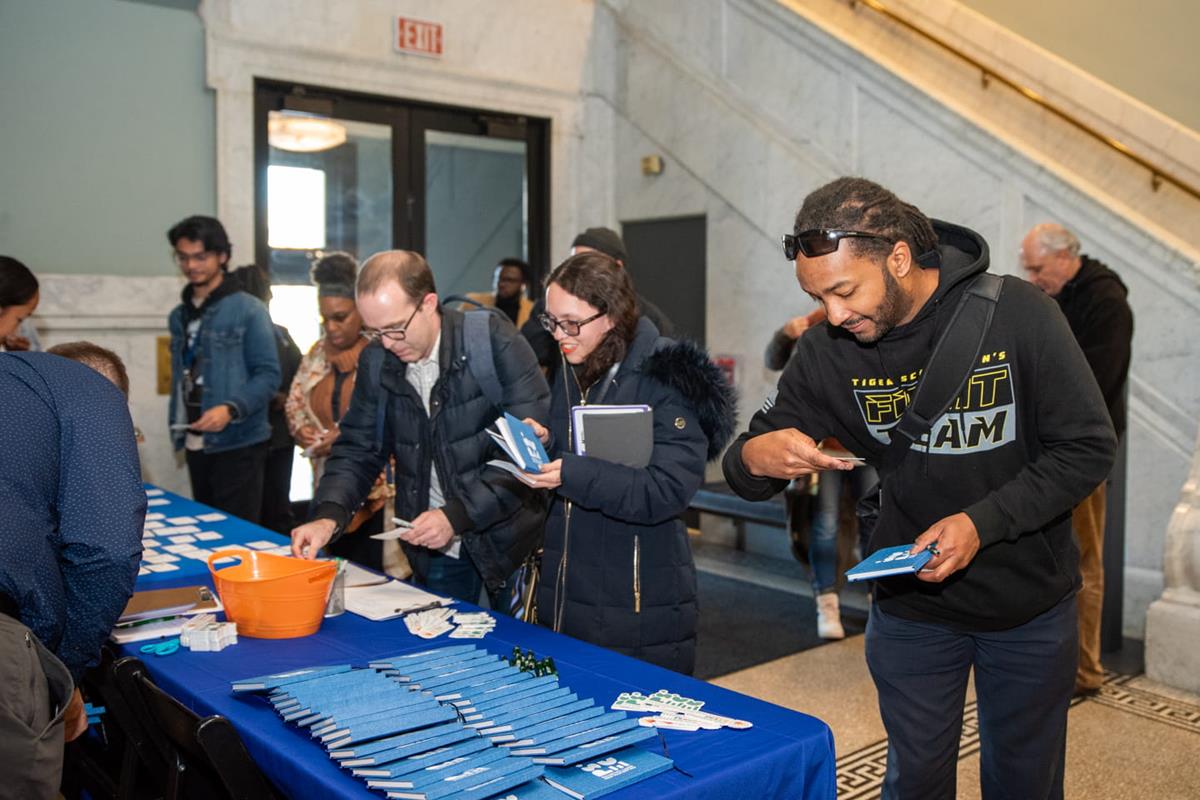 Several guests look at pamphlets on a table.