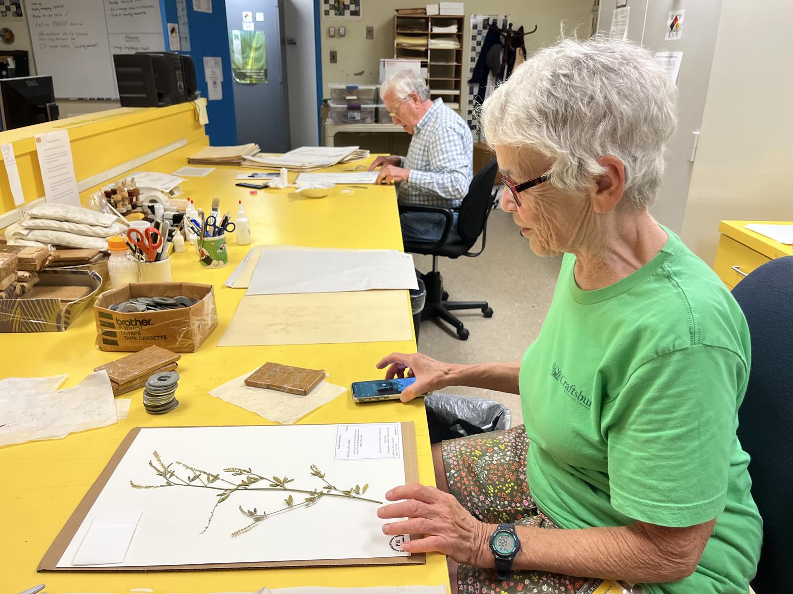Two volunteers looking at their finished plant press in the Botany department.