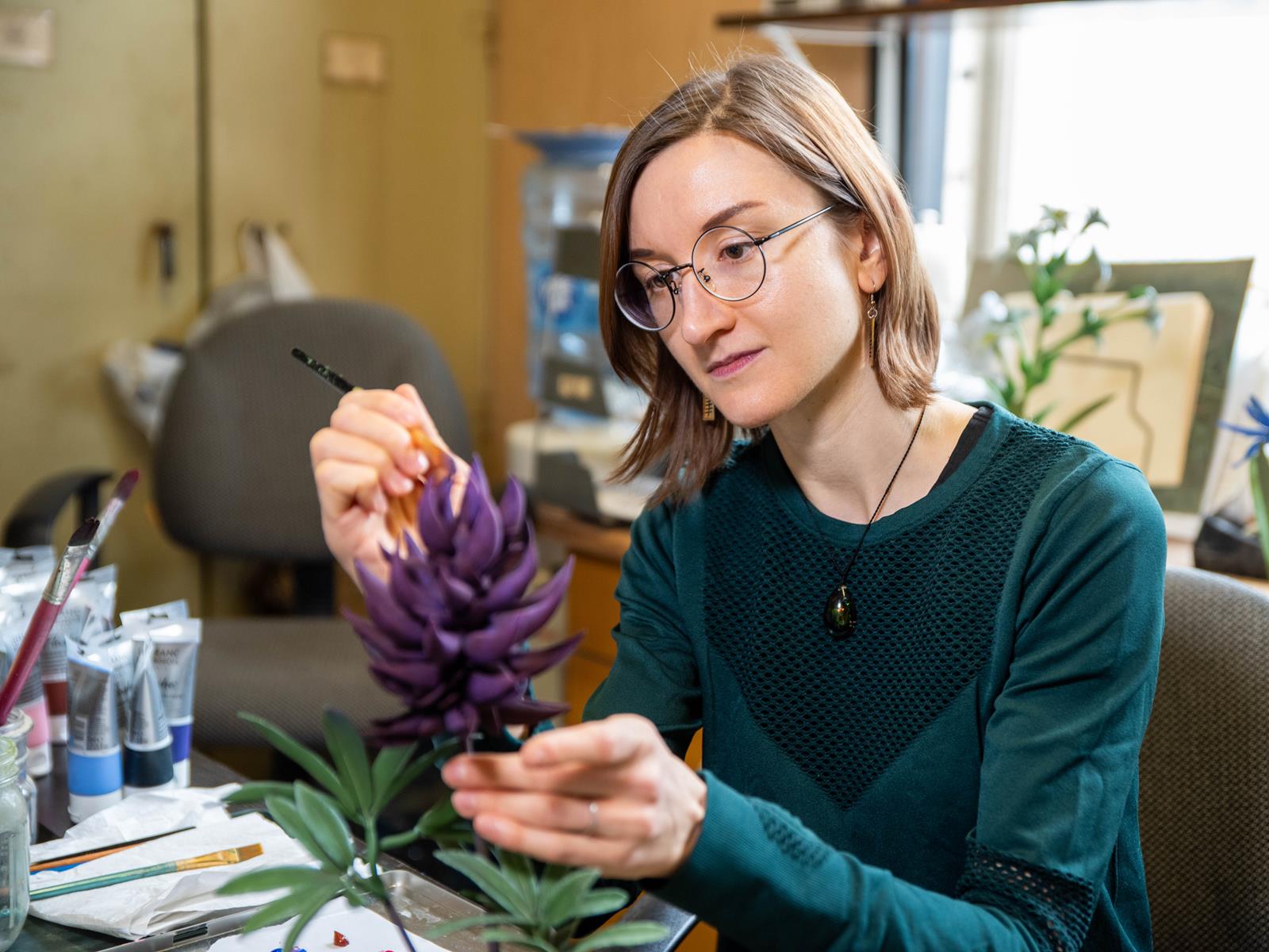 Artist, Lindsay Lindhult, hand painting a plant model.