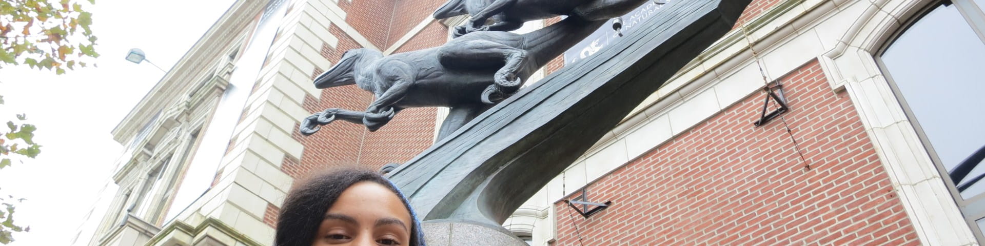 Aja Carter in front of statue at Academy of Natural Sciences