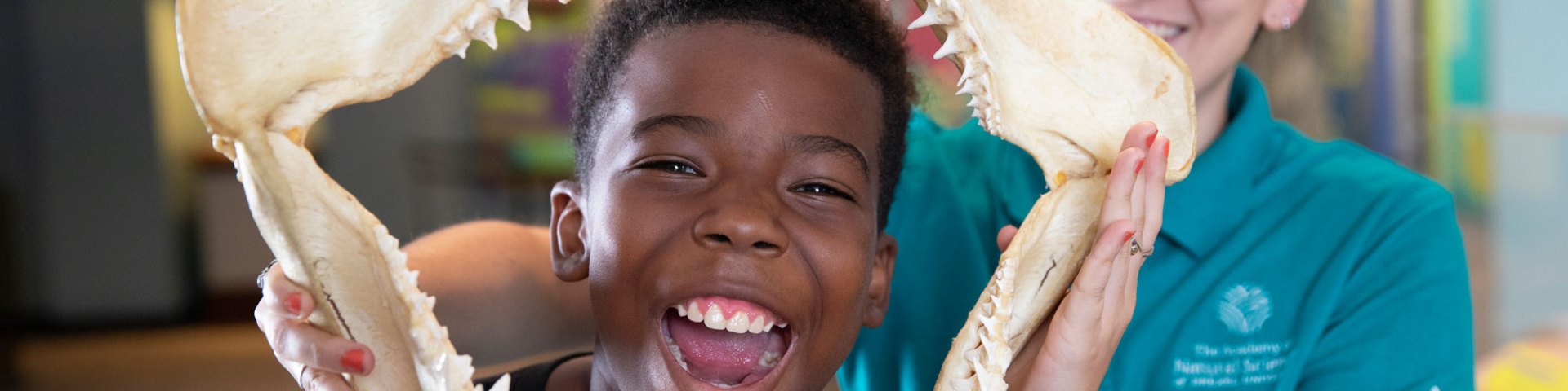 Educator holds large animal jaw around child's face