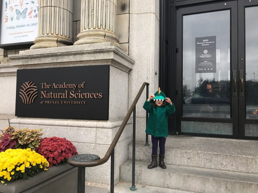Kid in Dino costume in front of museum