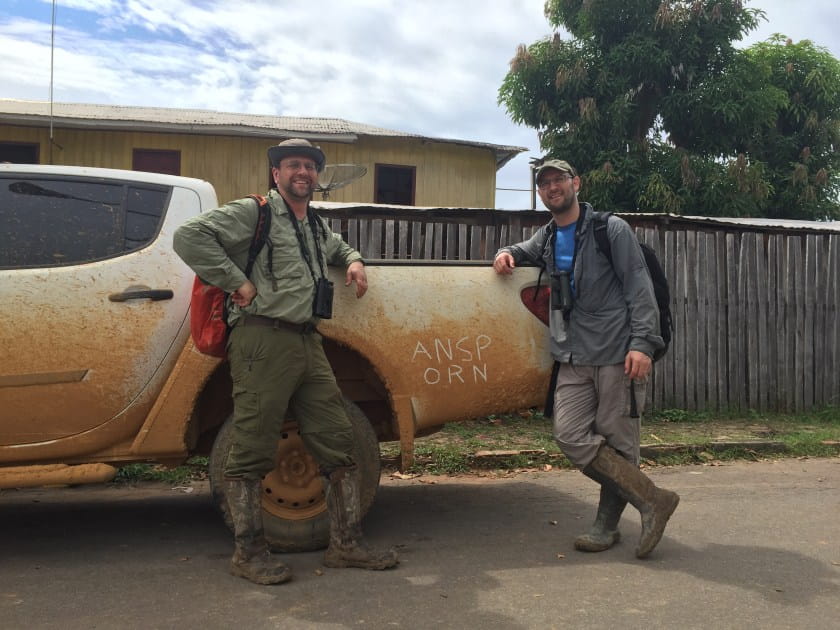 Scientists stand in front of muddy truck with ANS ORN scratched into the mud on the side.