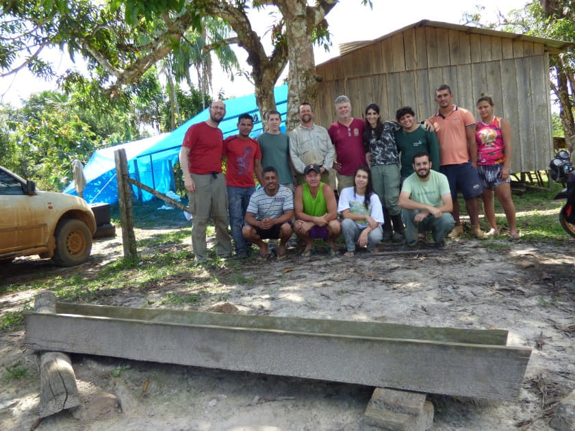 Group of scientists pose for group photo in front of wooden building