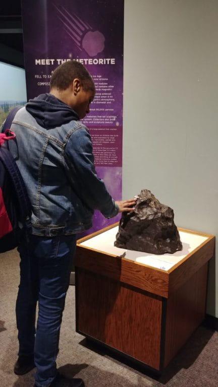 Young visitor touches the giant hunk of outer space in a unique experience.
