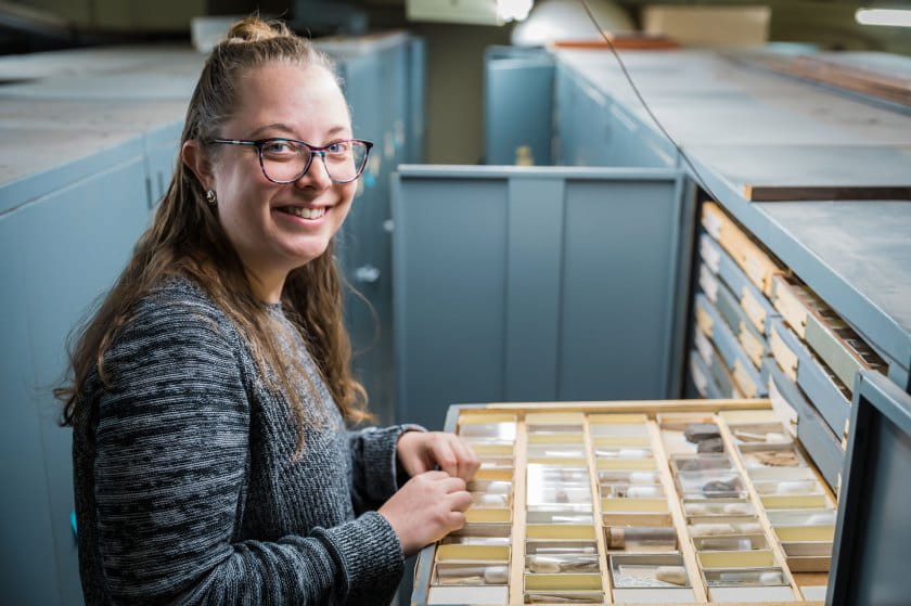 Female scientist with open drawer of invert paleo fossils