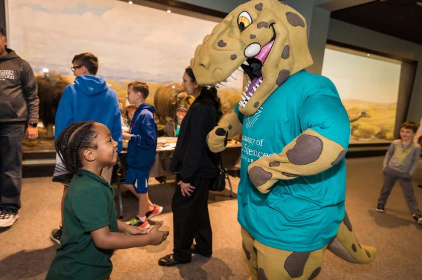 Young boy smiles up at Eddie the T. rex