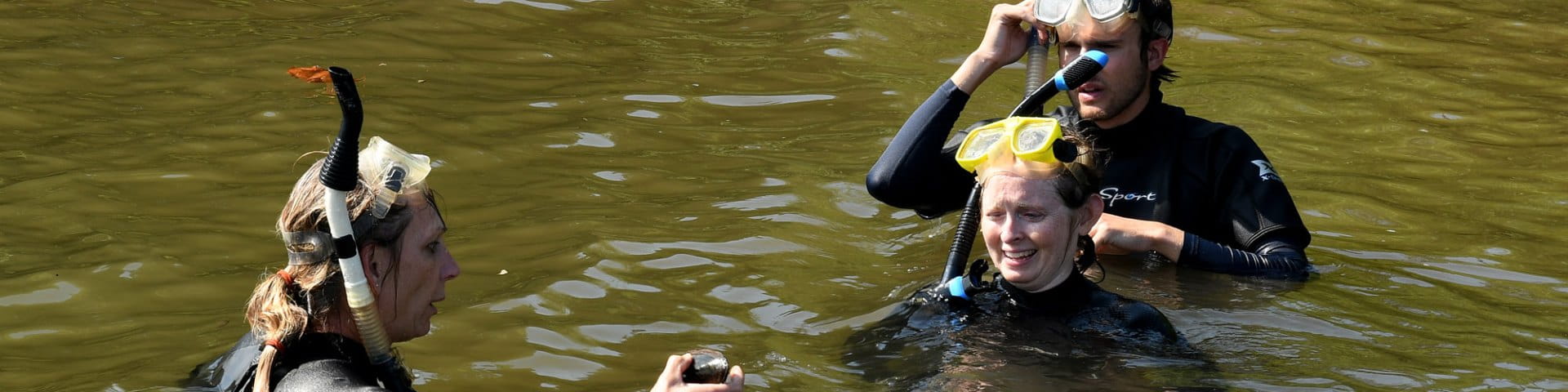 Three scientists in brownish river water