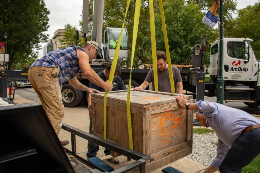 Large crate with fossil inside hoisted by crane