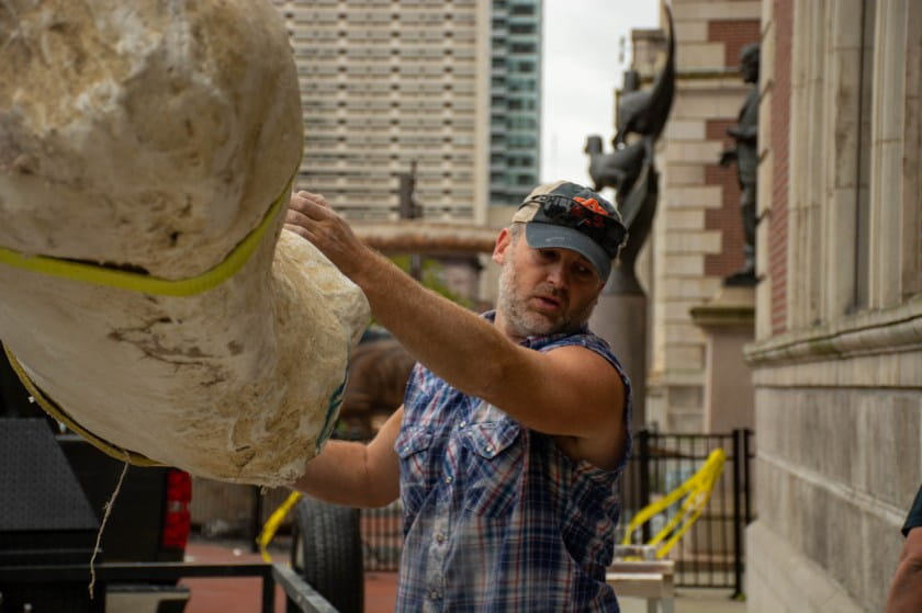 Man guides large fossil jacket off truck