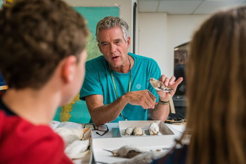 Male volunteer shows bird skin to young kids
