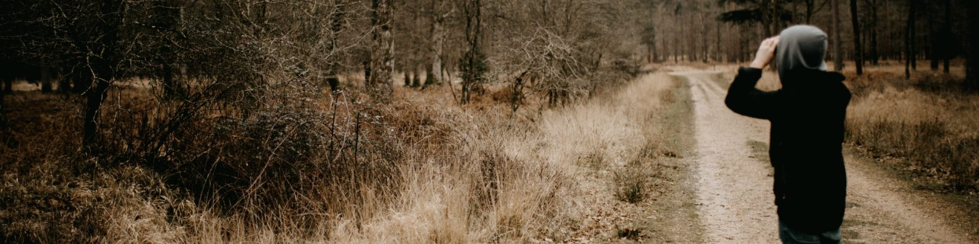 person in winter woods with binoculars