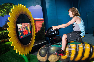 Boy on bee bike in Backyard Adventures exhibit. Photo by Imagine Exhibitions, Inc.