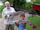 photo of scientist and boy holding large catfishes