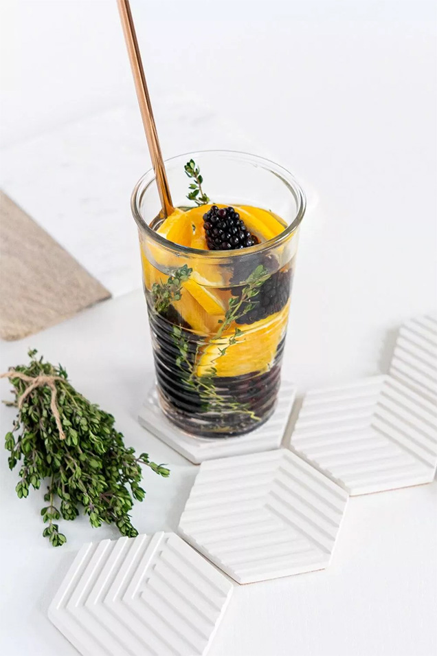 drink in glass with oranges and blackberries and straw with thyme next to glass