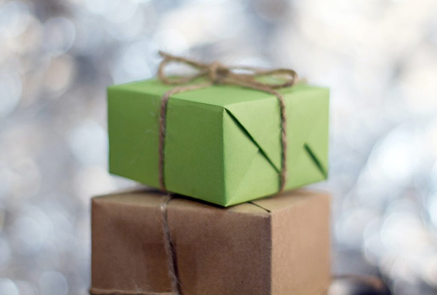 A brown gift sits underneath a light green gift, both with light brown strings.